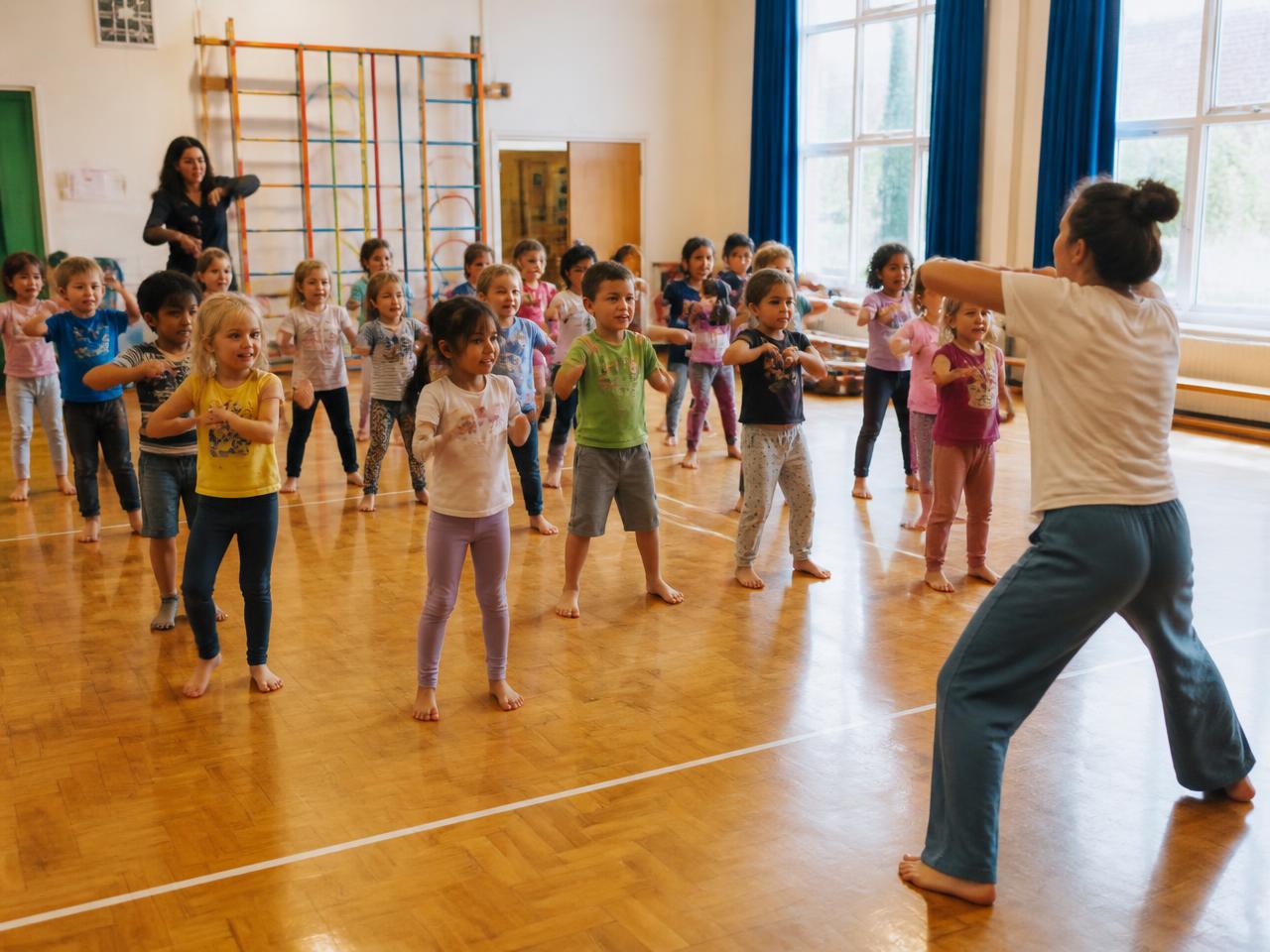 A large group of children moving together in a school hall led by two educators